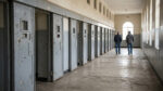 Deux hommes marchent dans un couloir historique avec des cellules de prison numérotées à Robben Island.